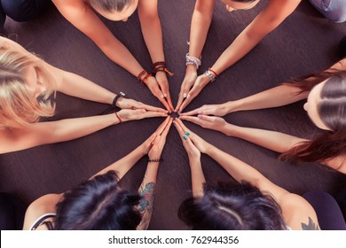 Close up hands of Group of sporty happy people sitting on the gym floor in a circle together, resting and meditating after yoga class with instructor indoors. Healthy lifestyle concept