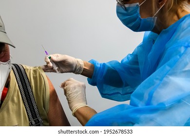 Close up of the hands of a healthcare worker who vaccinates an elderly person with a coronavirus Covid-19 vaccine. Hands in protective gloves hold a syringe with the vaccine. Selective focus. - Powered by Shutterstock