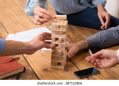 Close up of hands helping build a building of wooden pieces. Businesspeople planning a new business strategy. Business team trying to generate new ideas with wooden bricks. Business risk concept.
