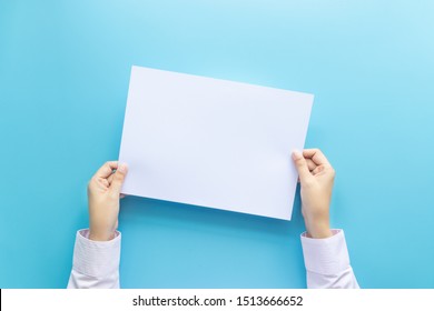 close up hands holding  empty white blank letter paper for flyer , presentation or invitation mock up isolated on a blue background.