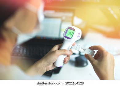 Close Up Hands Holding Infrared Thermometer That Showing High Temperature Fever And Antigen Rapid Test Kit Strep For Covid-19 That Appear Sign Of Positive Result. Self Check At Home When Have Symptom