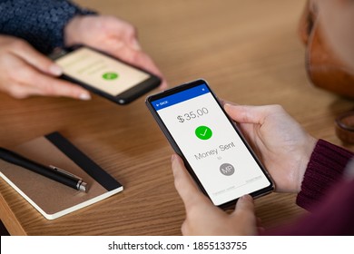 Close Up Hands Holding Mobile Phone With App For Send And Receive Money. Woman And Customer Holding Smartphone And Making Payment Transaction. Smart Phone Screen Displaying Digital Payment Sent.