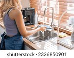 Close up hands of housewife washing dishes in at the kitchen sink. Attractive beautiful woman housekeeper wear apron, cleaning and rinse plate with water for housekeeping housework or chores in house.