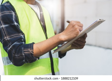 close up hands of inspector waer safety vest and checking list into clipboard - Shutterstock ID 1888212109