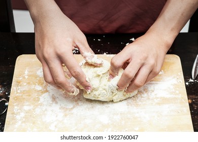 close up of hands kneading flour on a kneading board. 