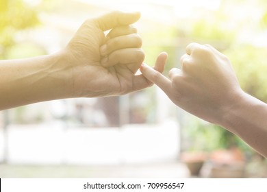 Close Up Hands Of Lovely Couple Hooking Each Other's Little Finger Together With Copy Space For Text And Soft Light Effect: Pinky Swear, Pinkie Promise Concept