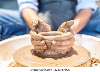 Close up hands make dishes from ceramic clay working on potters wheel traditional pottery craft - Powered by Shutterstock