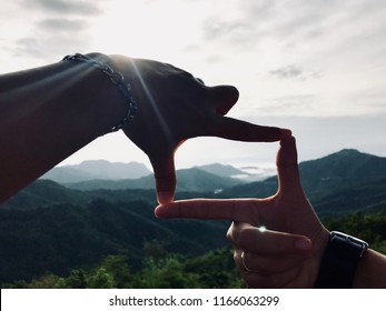 Close up of hands making frame gesture with sunlight on mountain,
Future planning, outdoor.