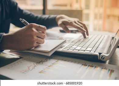 Close up hands man doing finances with using laptop and writing note at home office