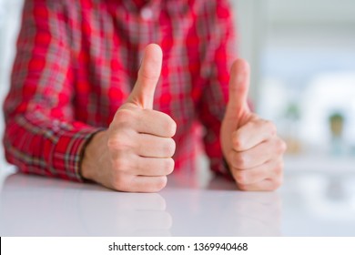 Close up of hands man doing thumbs up gesture over white table