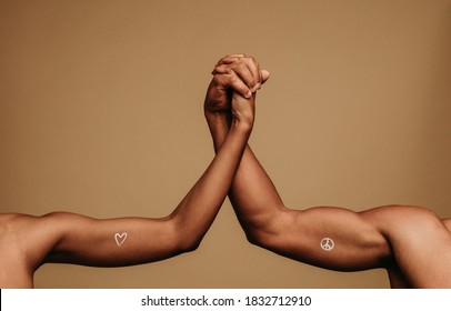 Close Up Of Hands Of Man And Woman Holding Each Other Showing Unity And Togetherness. Cropped Shot Of Two Arms Together With Symbols Associated With Black Lives Matter Painted On Them.