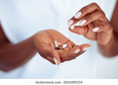 Close up hands of mature african woman taking beauty supplements for glowing skin. Black mid woman adding pills to heap of medicines. Middle aged female hands with bunch of medicines for healthy skin.