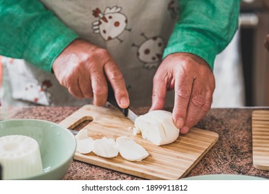 Close Up Of Hands Of Mature Man And Senior Cutting A Mozzarella With A Knife And Cooking Food To Eat