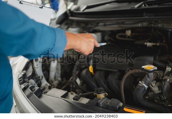 Close up\
of hand\'s Mechanic.  Young auto mechanic inspecting after engine\
maintenance. He pointed his pen at the\
engine.
