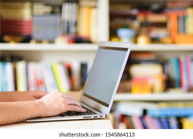 Close Up Hands Multitasking Man Using Notebook Computer In Library, Room Full Of Books Studying