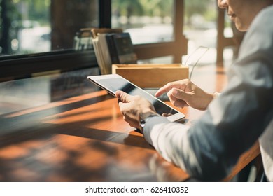 close up hands multitasking man using tablet, laptop and cellphone connecting wifi. Working just from cafe. Young man in smart casual wear working on digital tablet while sitting near window.
