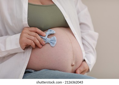 Close Up Hands On Pregnant Mother Holding Baby Clothes, Two Blue Bows. Lover Woman Waiting Child. Preparation For Childbirth, Girl Big Belly Advanced Pregnancy.