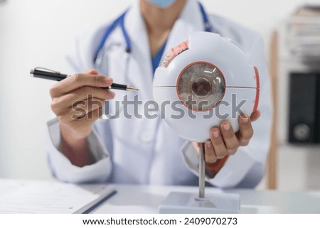 Close up hands of ophthalmologist with eye model for education concept, working with white desk medical room.