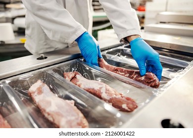 Close up of hands packing meat with vacuum heat sealing machine for food pack in meat factory.