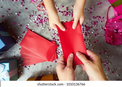 Close up hands of parent giving a red envelope or money red packet to child . Chinese new year and Lunar new year festival concept background . Top view .