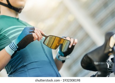 Close up of hands of professional female cyclist holding and putting on protective glasses while getting ready for training outdoors - Powered by Shutterstock