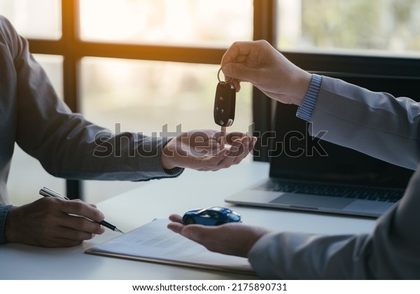 Close up of\
hands. Sale-man is selling and buying a car with loan agreement and\
financial between client.