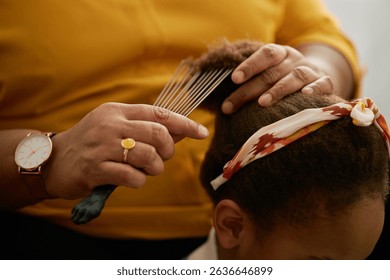 Close up of hands of senior grandmother using wide tooth comb for styling Black girls hair while caring for granddaughter at home - Powered by Shutterstock - Get 15% off with code: PIKWIZARD15