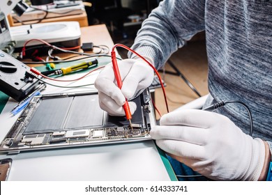 Close up hands of a service worker repairing modern tablet computer.  Repairing and service concept.