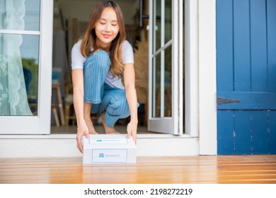 Close Up Hands Of Sick Asian Woman Sitting At Door To Receive Medication First Aid Pharmacy Box Package From Hospital Delivery Service At Floor Home, Drugstore Internet Online Medical Business