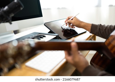 Close up hands song writer composing music note on tablet. Professional composer Recording Mixing and Mastering in home studio with keyboard and guitar. Digital music production