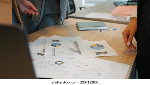 Close up hands of team analysing data for next term inveting strategy working in office. Papers with analytics are being discussed by workers in context of business. - Shutterstock ID 2207122835