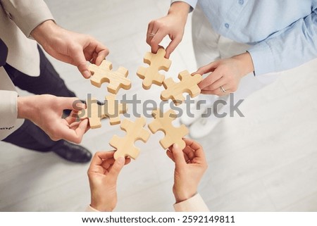 Close up hands of team assembling jigsaw wood puzzle, joining pieces to search idea, right solution, successful teamwork help and support, developing new concept, strategy brainstorming plan together