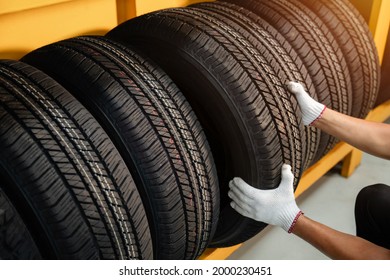 Close to the hands of a tire changer in Large warehouse of car tires, rack with customer car tires in warehouse of a tire dealer - Shutterstock ID 2000230451