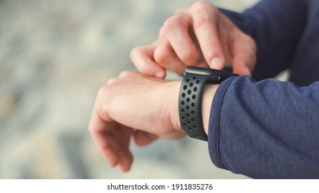 Close up hands tired sportsman wearing sportswear standing outdoors resting after a workout and using the smartwatch checking heart rate. - Powered by Shutterstock