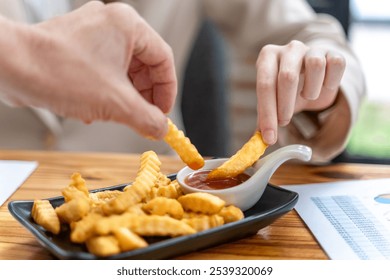 Close up hands of two people holding a french fried dipping in ketchup - Powered by Shutterstock