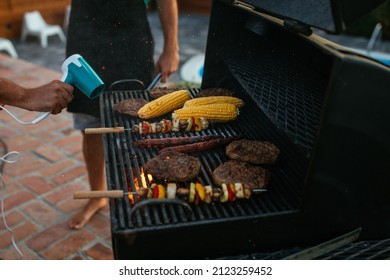 Close Up Of Hands Of Unrecognizable Man Who Is Kindles A Fire With Hair Dryer While Barbecuing