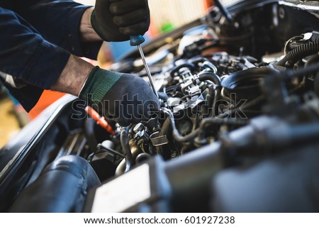 Close up hands of unrecognizable mechanic doing car service and maintenance.