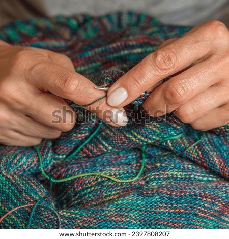 Close up of hands of unrecognizable woman knitting handmade clothes with spokes using  wool yarn. Concept of leisure activity.Knitting from yarn on  coarse spokes.