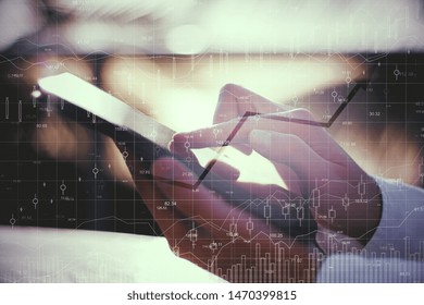 Close up of hands using device with forex chart on blurry background. Technology and currency concept. Double exposure