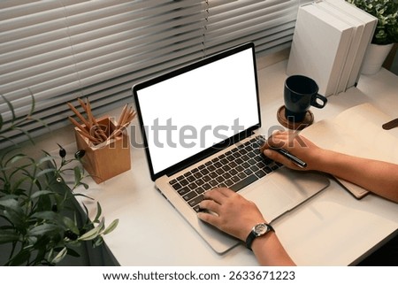 Close up of hands using a laptop with blank screen at a tidy desk