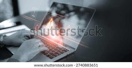A close up of hands using a laptop with multiple red warning signs and alert pop-ups on the screen. Concept of cyber security breach, computer virus, hacking attack, and digital system error.