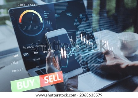 Close up of hands using laptop and smartphone with forex chart and sell, buy buttons on blurry background. Stock exchange, cryptocurrency and global fund information concept. Double exposure