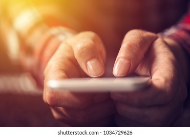 Close up of hands using mobile phone, selective focus on thumbs