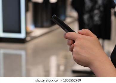close up hands using smart phone in clothing store. blur background