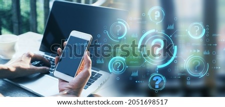 Close up of hands using smartphone and laptop at desktop with blurry abstract question mark interface. Problem solving and faq concept. Double exposure