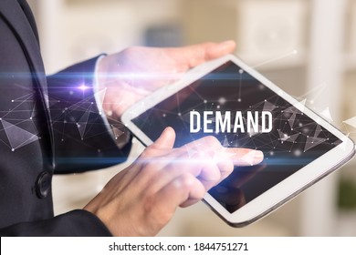 Close up hands using tablet with DEMAND inscription, modern business technology concept
