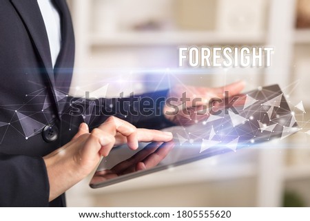 Close up hands using tablet with FORESIGHT inscription, modern business technology concept