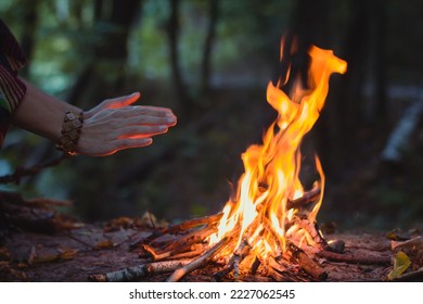 Close up hands warming over campfire concept photo. Make fire in forest. Side view photography with woman hands on background. High quality picture for wallpaper, travel blog, magazine, article - Powered by Shutterstock