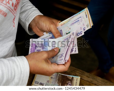 close up of the hands of a woman counting fifty tousand colombian pesos courrency 