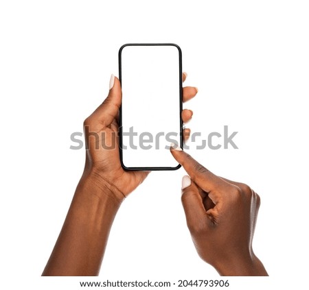 Close up hands of woman showing smartphone against white background. African woman hands touching blank screen of cellphone over white wall. Close up hands using app on mobile phone. 商業照片 © 
